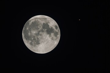 Fototapeta premium Bright full moon illuminating the night sky with a small Mars nearby