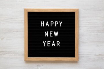 Celebratory New Year message displayed on contemporary sign against a white wooden backdrop, top-down perspective, flat lay, overhead view with ample space for text.