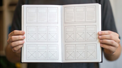 Startup funding pitch person holds open sketchbook displaying blank layout templates for startup funding pitch ideas