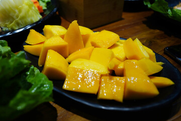 Freshly Sliced Ripe Mango on Black Plate with Salad