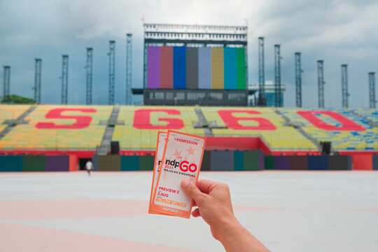 Singapore Jul04 2025 - Person holding up tickets for SG60 NDP National Day Parade preview in front of the Padang, where the annual event will be held on Aug 09 to commemorate Singapore's independence