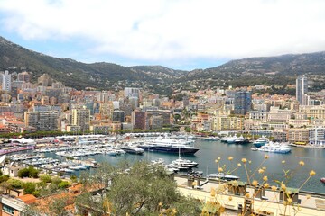 Luxury yachts anchored in Port Hercule, Monaco, with a panoramic view of the Prince’s Palace and...
