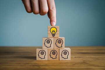 Leadership and innovation concept with lightbulb on top of wooden block pyramid.