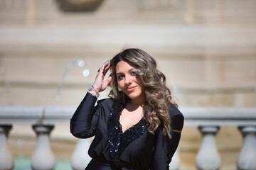 Portrait of blonde woman with curly hair, young and beautiful dressed in black. The woman is happy...
