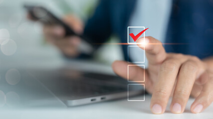 Close-up of hand touching digital checklist with red check mark icon on touchscreen, representing...
