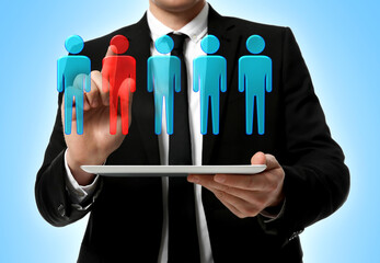 Dismissal. Businessman choosing human figure on virtual screen above tablet computer against light...