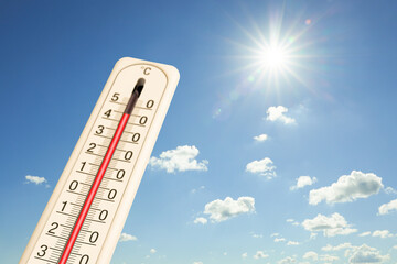 Extremely high temperature on thermometer against blue sky on sunny day. Summer weather