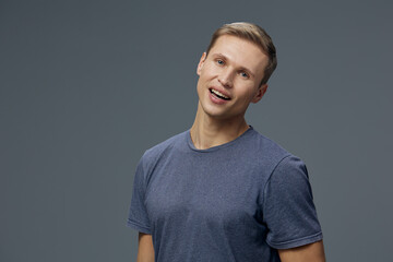 young smiling caucasian man in blue t-shirt look camera isolated on grey background digital detox...