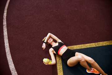 Sportswoman resting on the ground of outdoors sports gym