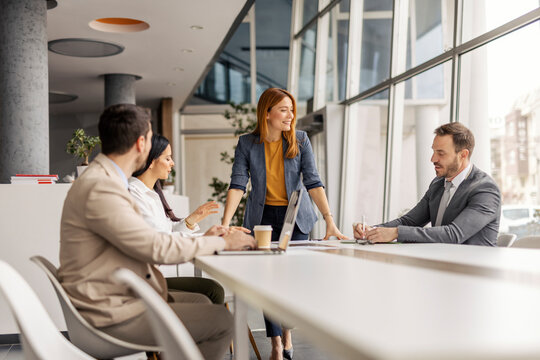 Female manager standing at corporate office with her leadership team and discussing business plan.