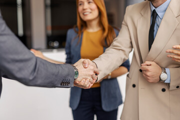 Close up of leaders shaking hands at corporate office.