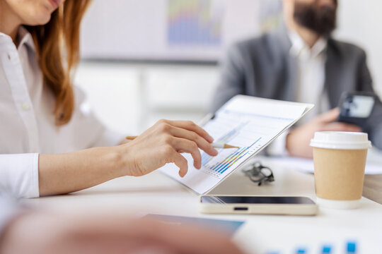 Close up of businesswoman's hands holding paperwork with charts and statistics.