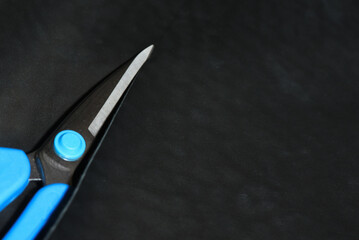 Scissors and a piece of leather, leatherworking top view background.