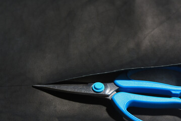 Scissors and a piece of leather, leatherworking top view background.
