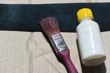 Glue, brush and leather on leatherworker table, leatherworking top view close up background.