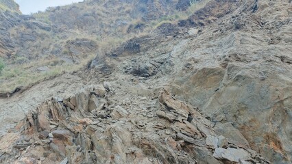 Rocky Mountainside, Dry Grass, Grey and Brown Tones, Rugged Texture, Natural Landscape, High-Angle View,  Geological Formation,  Erosion,  Arid Climate.