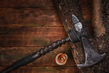 Medieval Viking axe on old warrior table in the light of burning candle close up background.