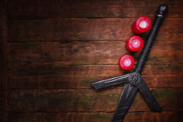 Old long medieval two handed knight warrior sword on ancient table in the light of burning candles...