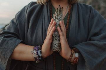 Close-up of female hands holding natural incense. Tools for ritual, energetic cleansing, and inner peace through aroma, intention, and mindful presence. Vintage tone. Soft focus, blurred