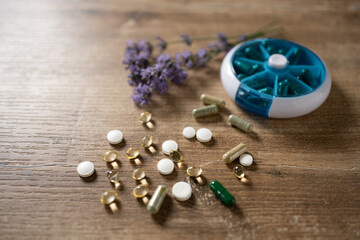 Colorful assortment of capsules and tablets beside a weekly pill organizer and lavender flowers