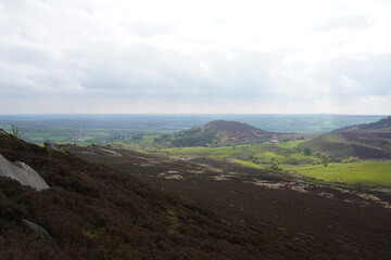 Scenic view of heather-covered hills and rolling green valleys under a cloudy sky in The Peak...