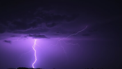 Dramatic purple lightning illuminating a stormy night sky, capturing raw natural energy.