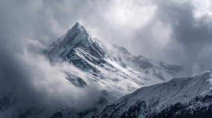 Obraz premium Majestic snow mountain peak shrouded in mist and clouds
