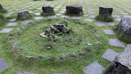 This image depicts an outdoor arrangement of large, weathered stones forming a circular pattern on...