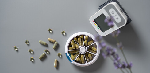 Health management essentials featuring herbal capsules and a digital monitor on a gray surface...
