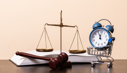 Golden scales of justice, judge's gavel, open book and alarm clock