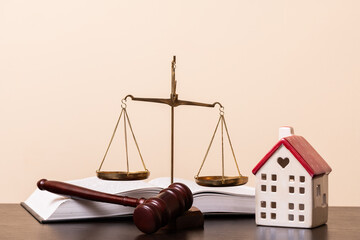 A judge's gavel, an open book, golden scales of justice and a symbolic miniature house