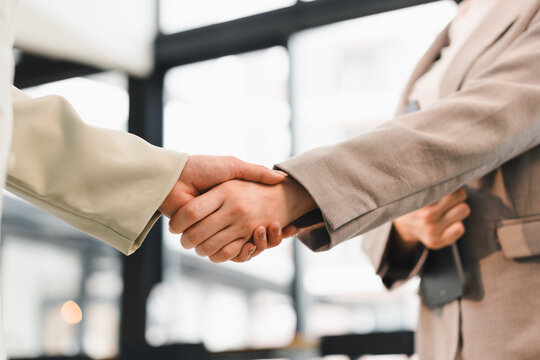 Business handshake between two people in office, one holding digital tablet, symbolizing agreement and partnership with professional atmosphere