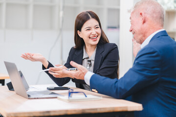 Young Asian businesswoman and senior Caucasian businessman working together in modern office,...