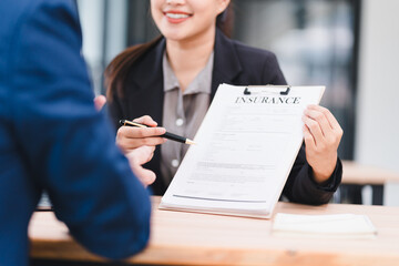Smiling businesswoman holding insurance document, discussing contract details with client at office...