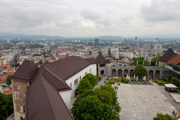 An expansive elevated view looks down upon the courtyard and buildings of Ljubljana Castle, with the sprawling city of Ljubljana