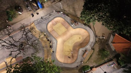 Top view on skatepark pool and professional cool skateboarder ride with flow and style. Skateboard man perform tricks, ride inside skate park in urban city area, Drone aerial shot of skateboarding - Powered by Adobe