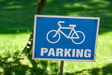 Blue bicycle parking sign stands out in a lush green park area