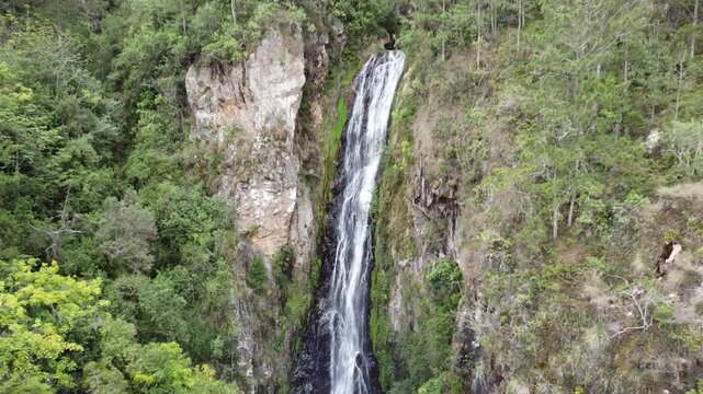 Stunning aerial view of a winding road through mountainous, forested terrain in Aguas Blancas, Constanza, Dominican Republic. Captures travel, natural beauty, and the serenity of remote landscapes.