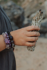 Close-up of female hands holding natural incense. Tools for ritual, energetic cleansing, and inner...