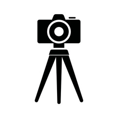 A camera on a tripod. It's a black silhouette on a white background. The tripod has three legs and the camera has a simple lens.
