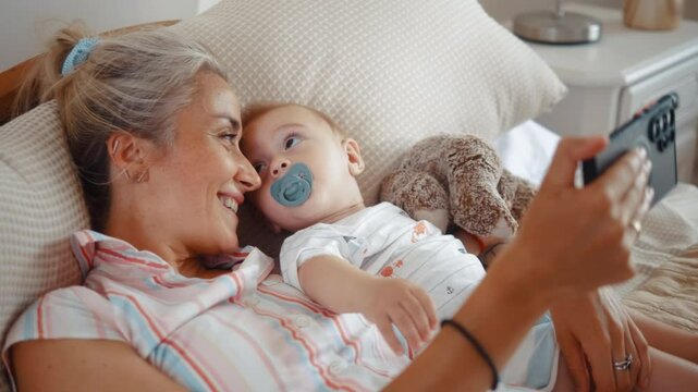 Mother and baby relax lying in hotel room bed during summer vacation, intimate mom and baby family love moments