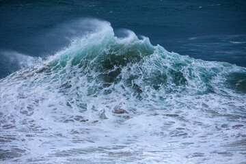 Two huge foamy waves collide and flare high into the sky during an east coast low swell creating a textured liquid mountain.