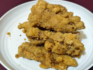 A plate of crispy golden fried chicken fillet, served on a blurred background.