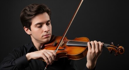 Young caucasian male violinist playing classical music on a dark stage