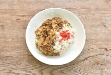 fried ground beef with onion or soboro donburi on rice black sesame topping pickled red ginger on plate
