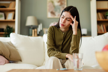 Young Woman in Pain Sitting in a Comfortable Living Room with Neutral Tones