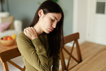 Young Professional Woman Experiencing Neck Discomfort While Working From Home In Natural Light Interior