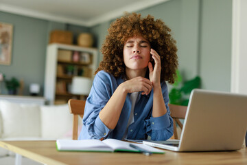 Young Professional Woman With Curly Hair Massaging Neck During Remote Work Session At Home Office Desk