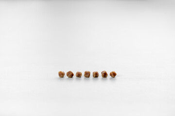 7 brown gallbladder lumps or pile gallstones lined up in rows from cholesterol or bad food on white...