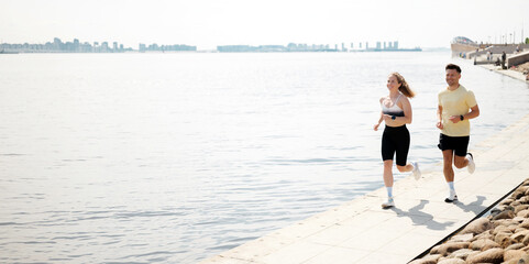 Joyful morning joggers enjoy the beautiful waterfront as they embrace fitness and nature under the...